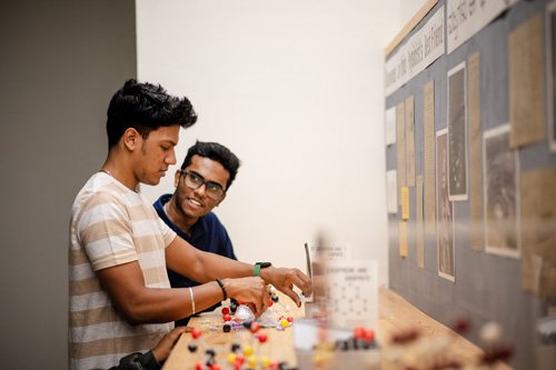 Two visitors building molecule models