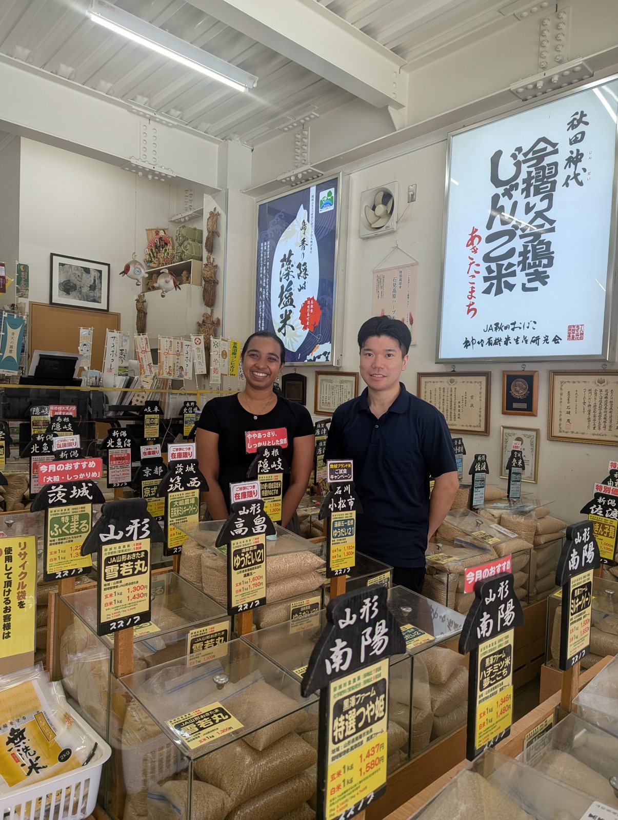 Two people in a rice store lined with signs