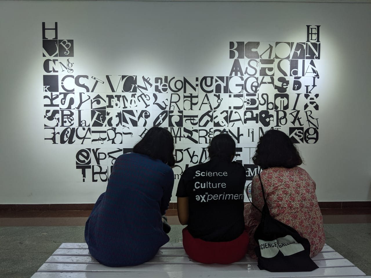 Visitors seated in front of a lettered wall