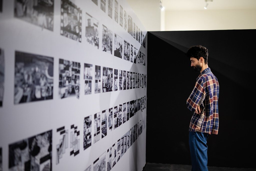 A visitor reading a wall of archival photographs