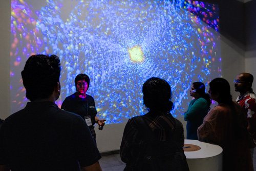 Visitors before a large glowing projection