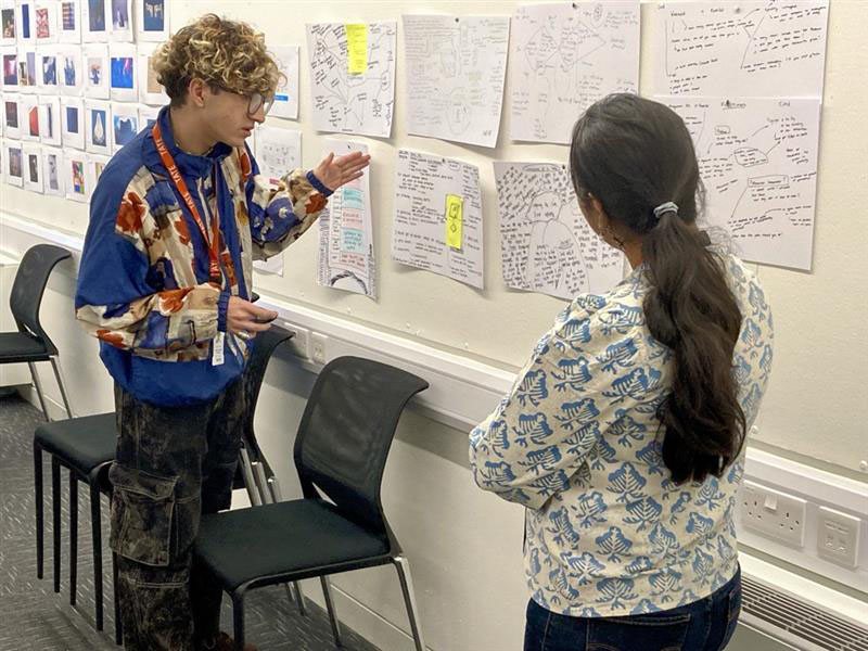 A participant presenting ideas in front of a wall of sketches