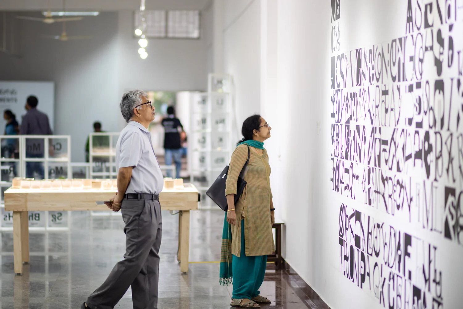 Visitors walking past a wall of hand-lettered element names