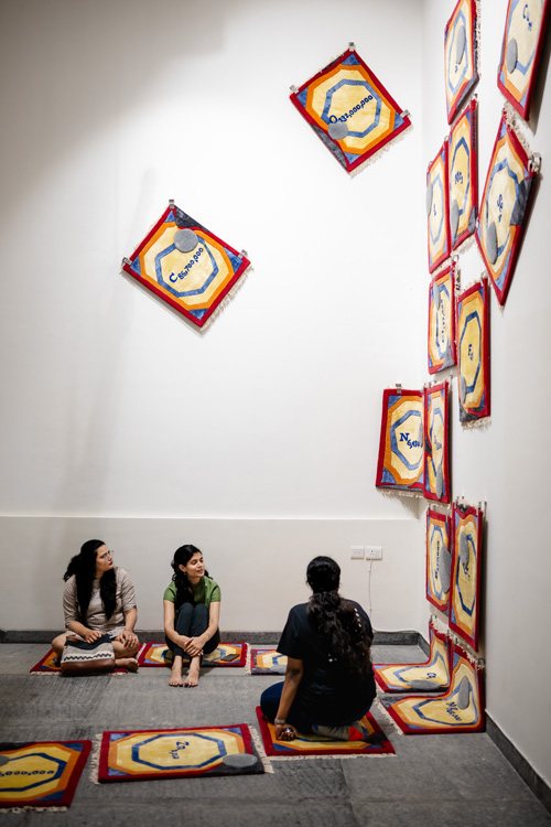 Visitors seated beneath hanging painted panels