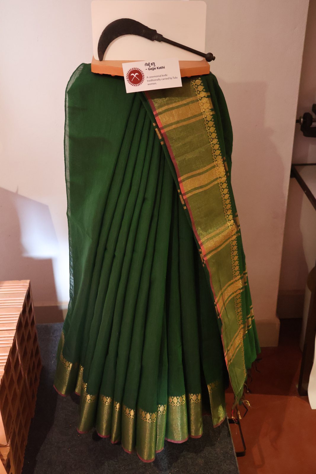 A green saree displayed on a stand